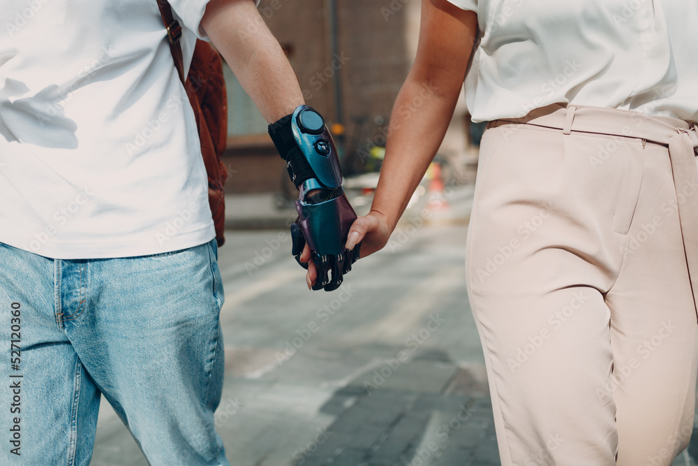 Young disabled man with artificial prosthetic hand walking and holding woman girlfriend hand