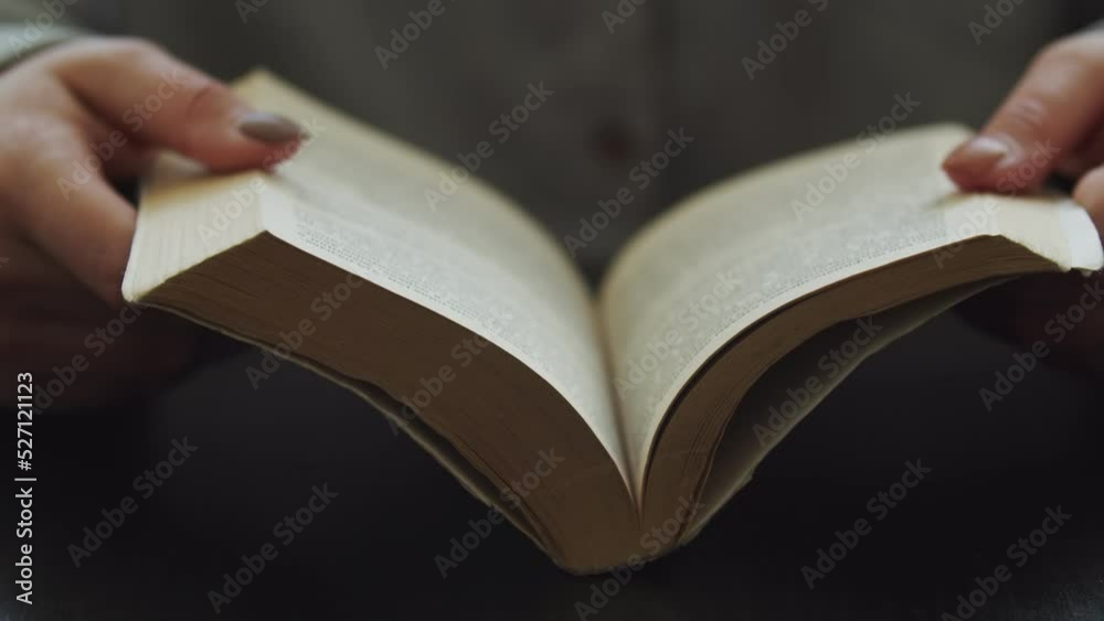 Female hands on the table hold a book and open it, close-up. The concept of learning of education