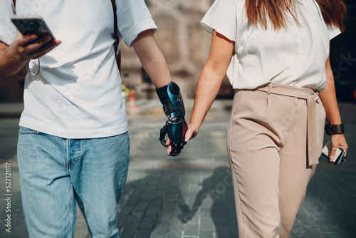 Young disabled man with artificial prosthetic hand walking and holding woman girlfriend hand