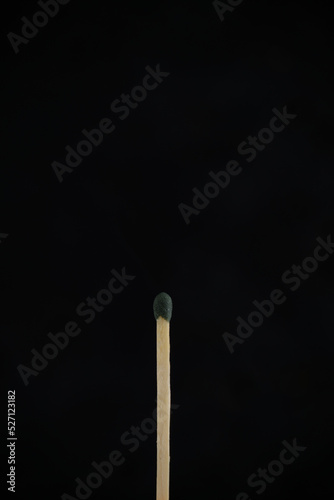 A match with green head on a black background.