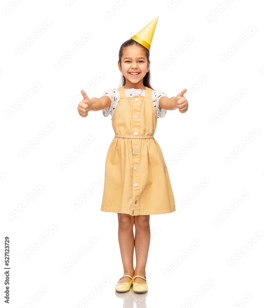 birthday, childhood and people concept - portrait of smiling little girl in dress and party hat showing thumbs up over white background birthday, childhood and people concept - portrait of smiling little girl in dress and party hat showing thumbs up over white background