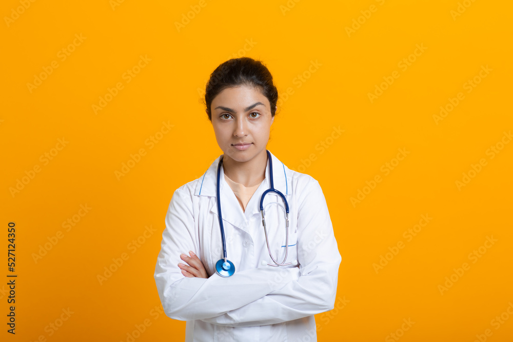 Portrait of indian doctor woman in white medical gown stethoscope isolated on yellow background.
