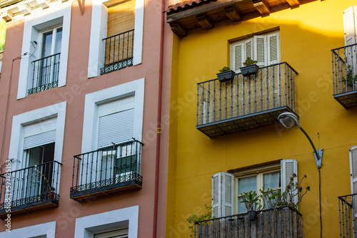 Yellow pink facades of residential apartment buildings houses in classical style. Balconies with plants, panoramic windows, doors with wooden shutters. European architecture details. Travel concept.