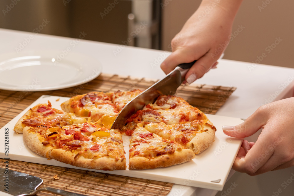 Cutting pizza with a large knife at home close-up