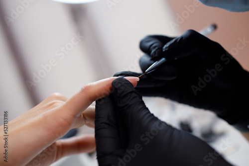 Manicure process female hands finger nails polish. Beautician in gloves