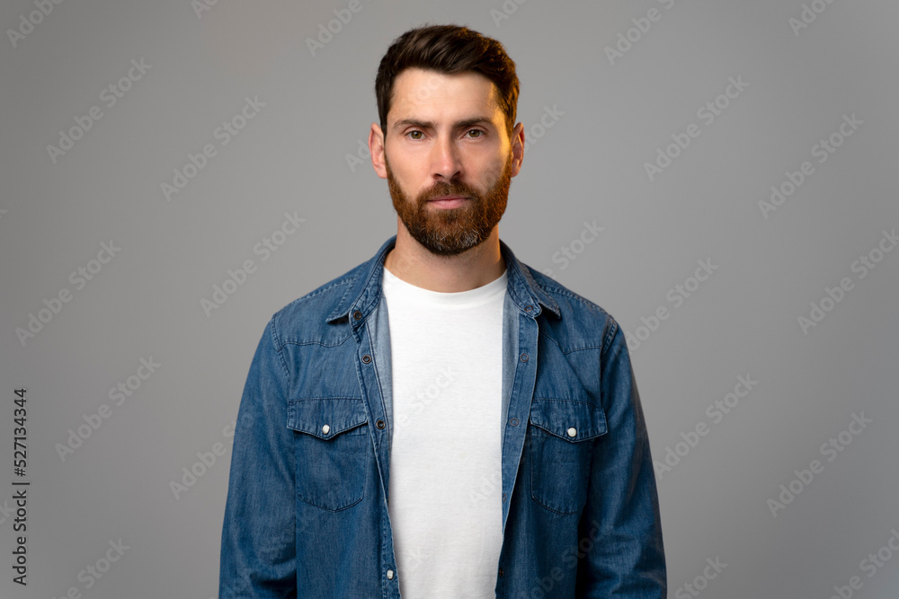 Fototapeta premium Attentive self confident bearded man looking at camera with serious expression
