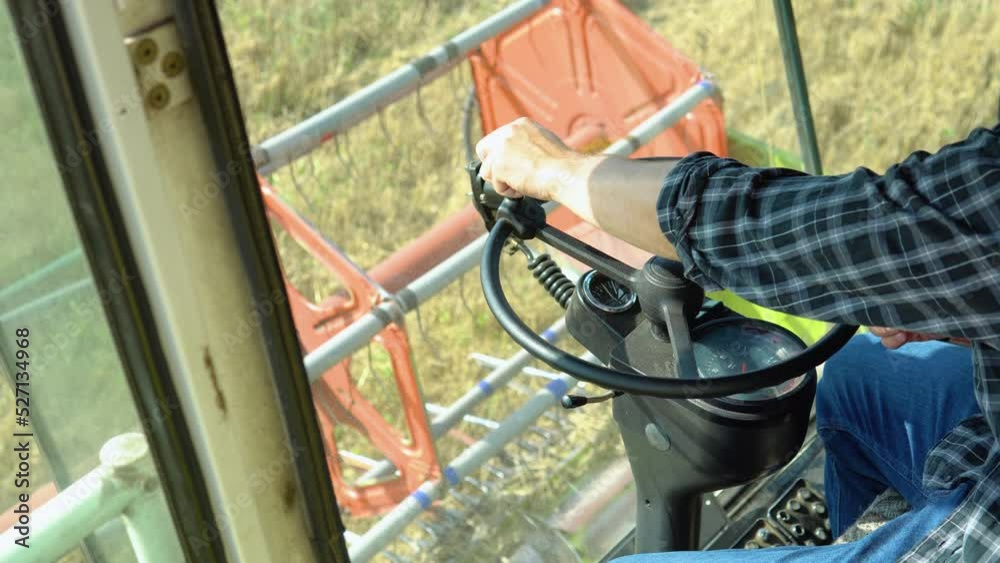 Male hands farmer driver on steering wheel combine harvest on agricultural field. View from inside tractor driver turns steering wheel agricultural machine Male hands farmer driver on steering wheel combine harvest on agricultural field. View from inside tractor driver turns steering wheel agricultural machine