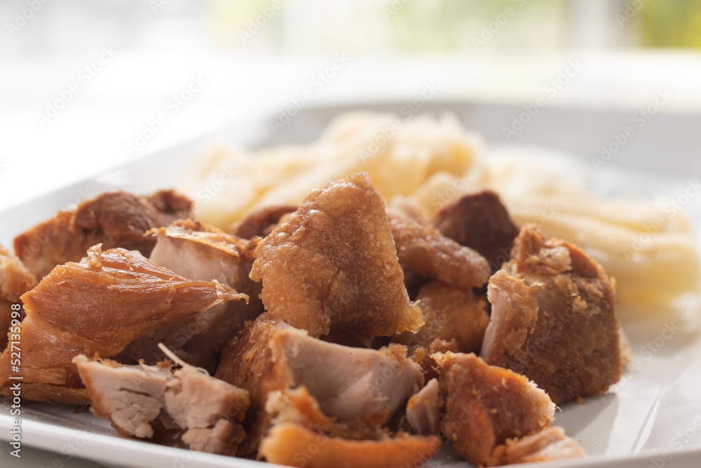 pork rinds with steamed root and sour milk cream served on a white dish