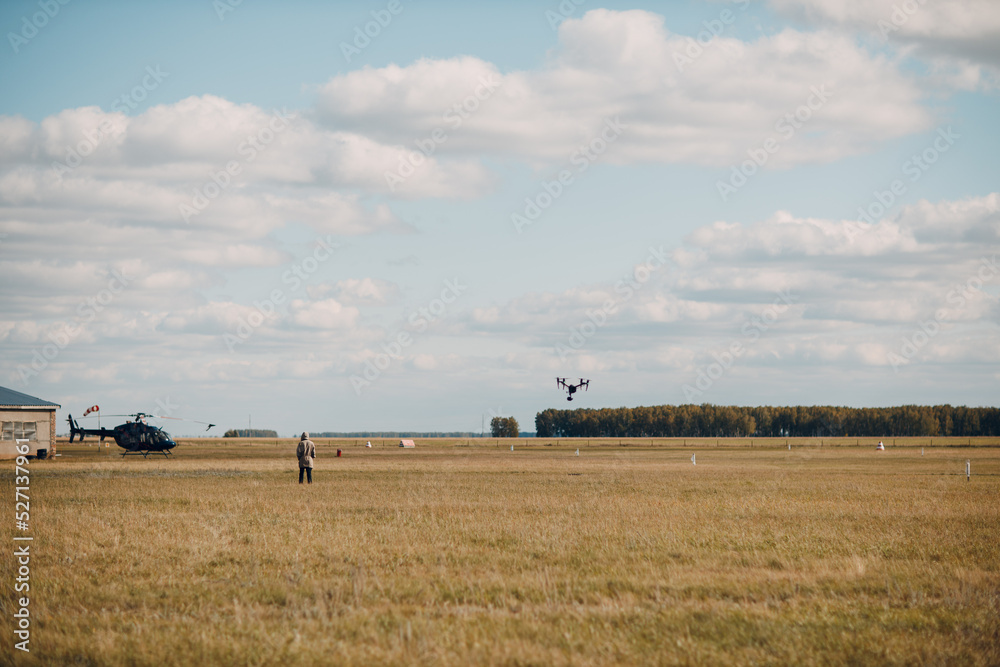 Big quadcopter drone on aerial flight and filming man and helicopter. Big quadcopter drone on aerial flight and filming man and helicopter.