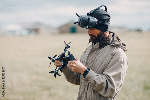 Man controlling fpv quadcopter drone for aerial photography and videography with goggles antenna remote controller.