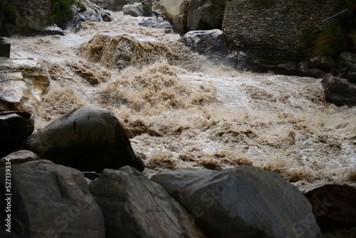 High-pressure flood water in mountain river tributary, caused by global warming, melting glaciers, and torrential rains. This has caused devastation in Pakistan

With selective focus  depth of field. photo