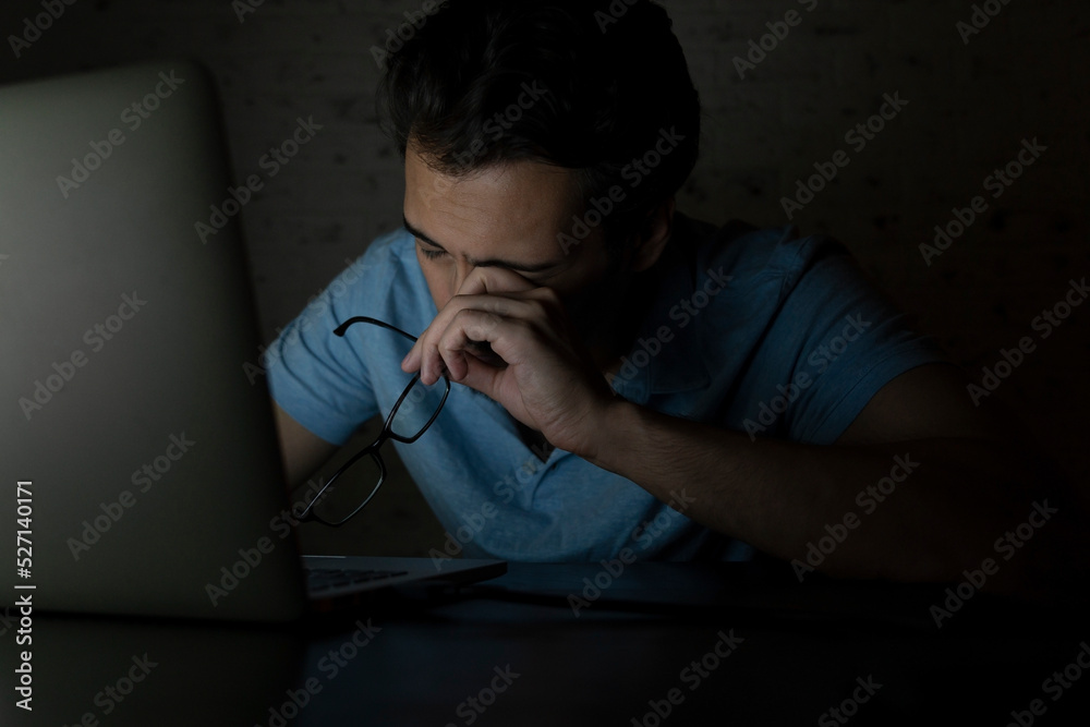 Tired man working on laptop at late night Tired man working on laptop at late night
