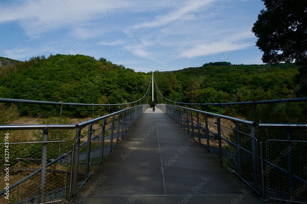 suspension steel bridge with a women on a bike driving on it