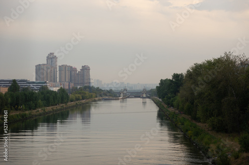 Khimki canal near the river lock - woodland on the bank of the canal, residential development in the distance - Moscow - Russia
