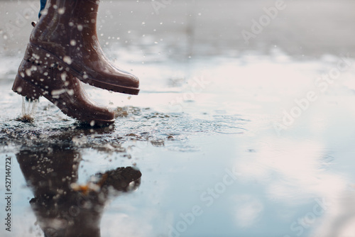 Wallpaper Mural Woman wearing rain rubber boots walking running and jumping into puddle with water splash and drops in autumn rain