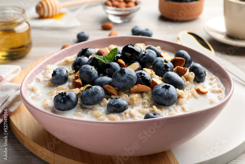 Tasty oatmeal porridge and ingredients served on wooden table, closeup. Healthy meal