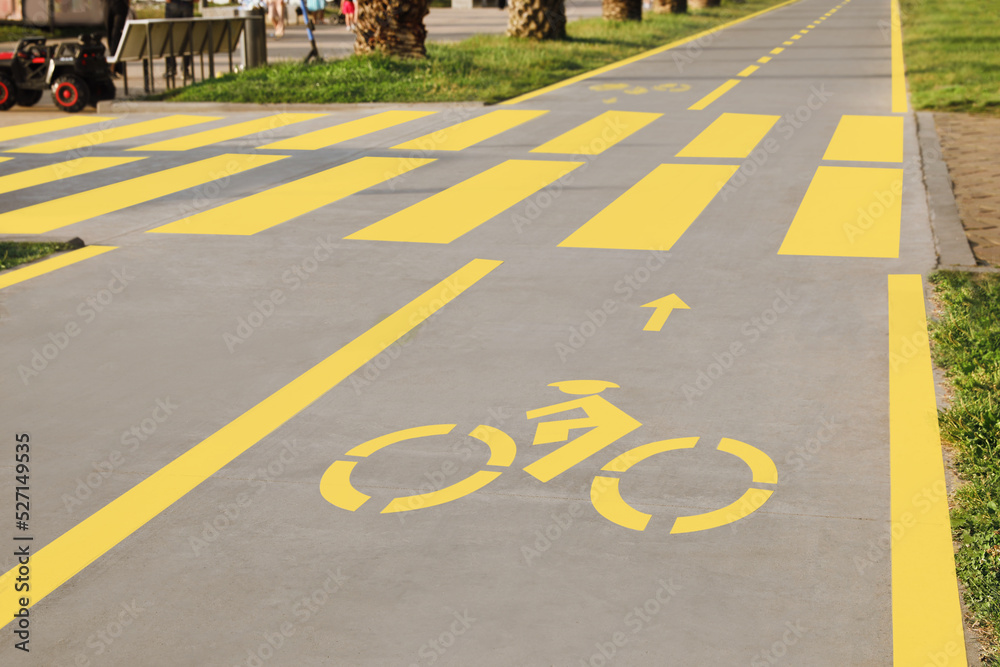Obraz premium Bike lane with painted yellow bicycle sign and pedestrian crossing outdoors