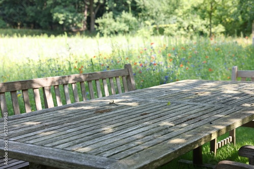 Empty wooden table with bench on sunny day in garden © New Africa