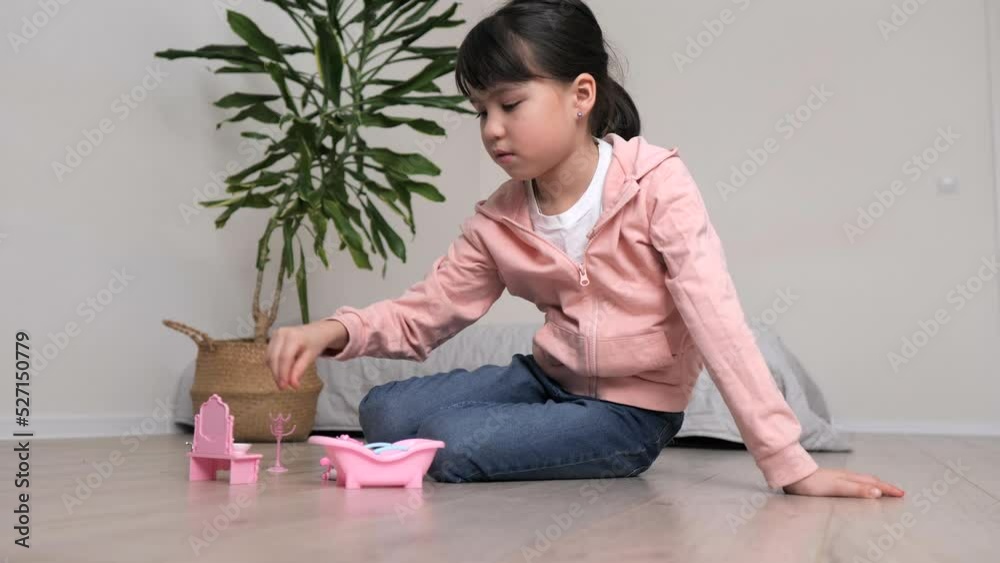 Cute little girl is playing with toys on the floor in white room. Kid have fun in her room. Cute little girl is playing with toys on the floor in white room. Kid have fun in her room.