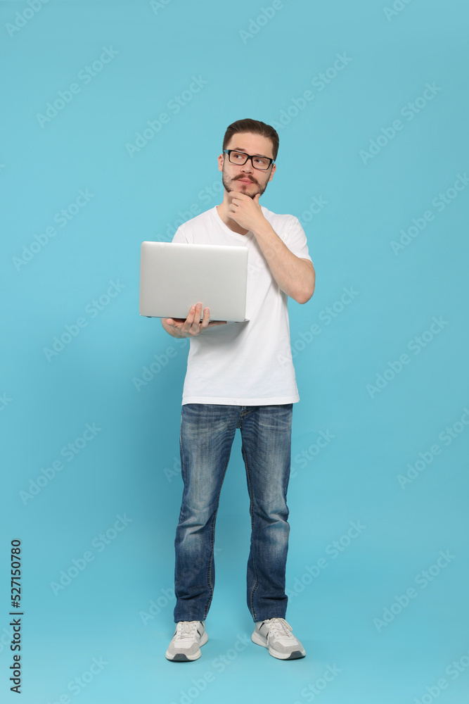 Pensive man using laptop on light blue background Pensive man using laptop on light blue background