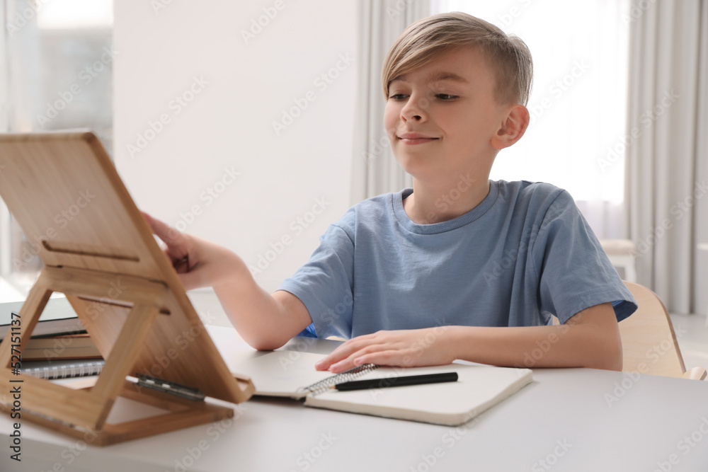 Boy doing homework with tablet at table indoors Boy doing homework with tablet at table indoors