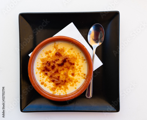 Just cooked burned cream, creme brulee, served in ramekin on table in restaurant. photo