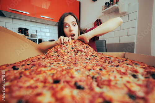 Canvas-taulu Hungry Woman Eating a Large Pizza by Herself in the Kitchen