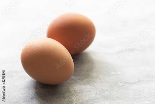 Two whole chicken eggs on a textured white background. photo