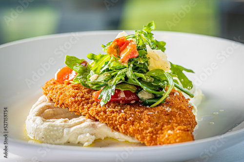 Fotografia Chicken Milanese topped with Arugula, Oven Dried Tomato and Parmigiano Reggiano