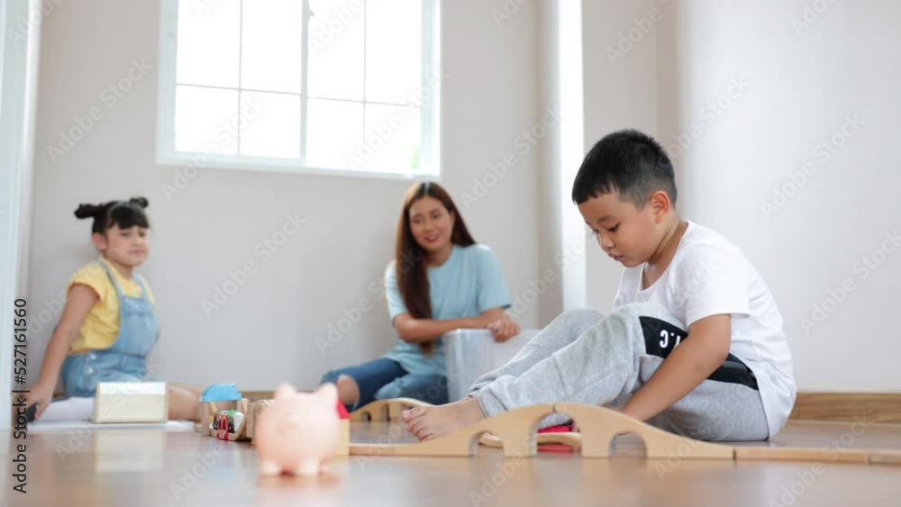 Cute asian boy playing wood block building rail way and road on the floor and his mother and sister help him to do that at home. Cute asian boy playing wood block building rail way and road on the floor and his mother and sister help him to do that at home.