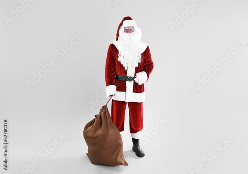 Full length portrait of Santa Claus with sack on light grey background