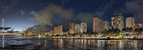 Panoramic of Ocean waters of Waikiki Beach at Night with Hotels aloing the coast