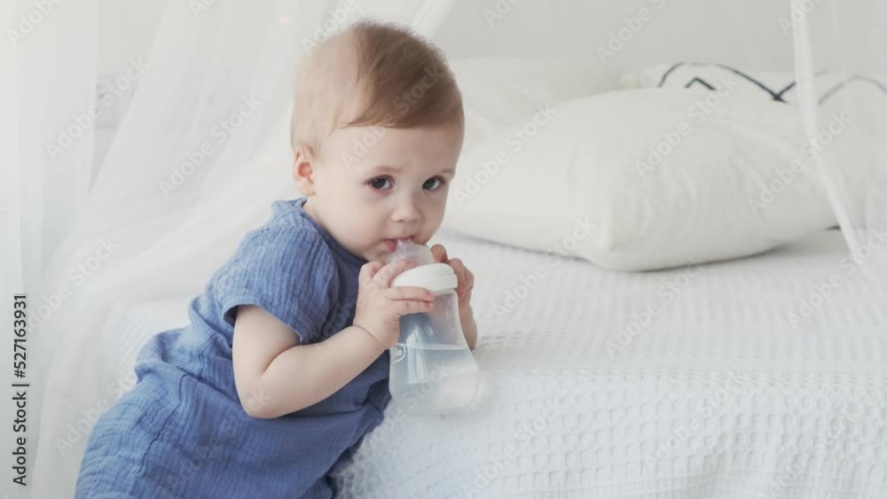 Close-up of a small child holding a bottle. Children's products. Happy loving family
Close-up of a small child holding a bottle. Children's products. Happy loving family