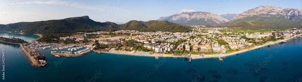 Scenic panoramic summer view of Kemer on Mediterranean coast at foot of Taurus Mountains overlooking residential buildings and marina. Famous tourist city and beach resort on Turkish Riviera