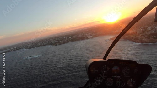 POV Flying in a helicopter over the coast during sunset in Sydney, Australia photo