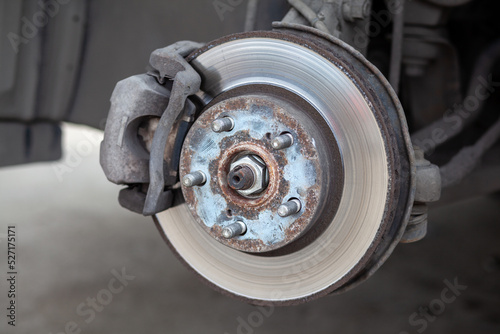 Disc brake of the vehicle for repair, in process of new tire replacement. Car brake repairing in garage.Suspension of car for maintenance brakes and shock absorber systems. Replacement of brake pads. © Анатолий Савицкий