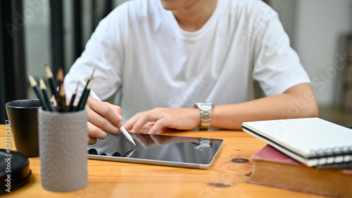 cropped image  A man in casual outfit sits at his desk using digital tablet