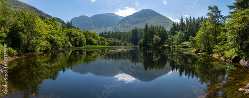 Fototapeta Naklejka Na Ścianę i Meble -  Small Scottish lake panoramic landscape,surrounded by trees at Glencoe,Scotland,United Kingdom.