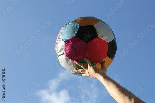 Photos Bola gigante de futebol colorida no céu azul.