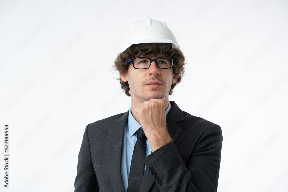 Portrait of young business man in black suit protective construction helmet, keeping hand on chin thinking about question isolated on white background. Portrait of young business man in black suit protective construction helmet, keeping hand on chin thinking about question isolated on white background.