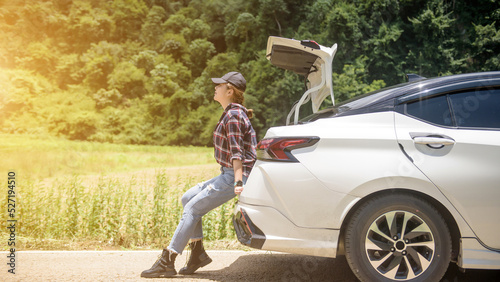 Tableau sur toile A female traveler with a backpack in a hatchback on a road with mountains in the background