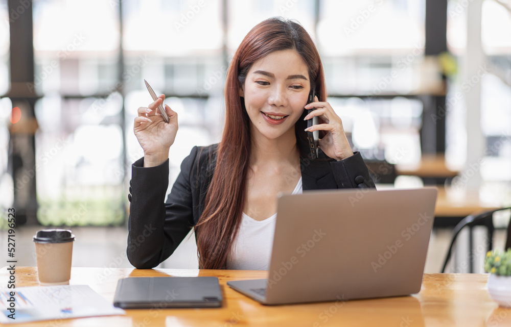 Young Business Asian woman talking on a smartphone and sitting on desk in workplace, Asian female Business accountant Documents data sitting at his workplace. Young Business Asian woman talking on a smartphone and sitting on desk in workplace, Asian female Business accountant Documents data sitting at his workplace.