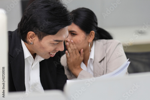 Business people gossiper group whispering or sharing rumor about their colleague in the office. Male coworker sitting and telling gossip to female workmate about bullying problem at work place.