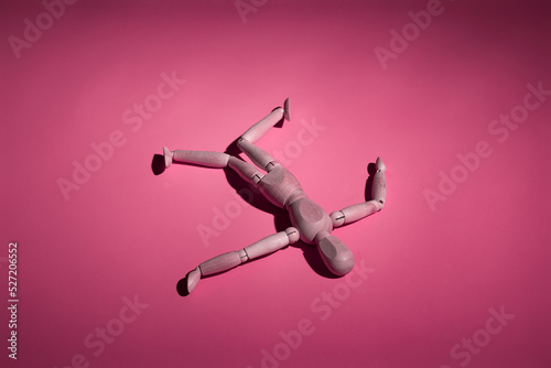 abandoned broken wooden mannequin lies on a pink background, top view