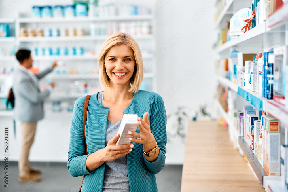 Happy woman buying in pharmacy and looking at camera. - obrazy, fototapety, plakaty 