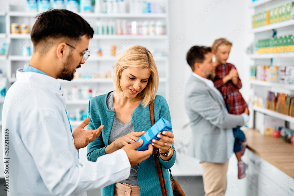 Mid adult woman chooses medicine with help of pharmacist in drugstore.