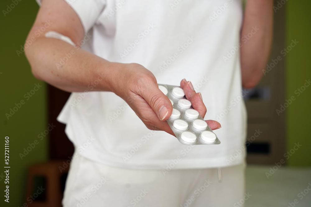 a woman with a plastered hand on the background of a hospital ward holds pills in a blister in her hand, addiction treatment a woman with a plastered hand on the background of a hospital ward holds pills in a blister in her hand, addiction treatment