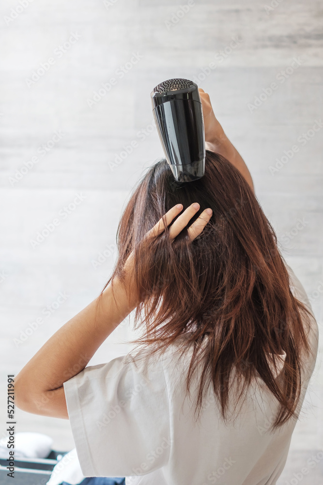 Fototapeta premium young woman using hair dryer at home or hotel. Hairstyles and lifestyle concepts