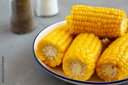 Homemade Steamed Corn on the Cob with Butter on a Plate, side view. Close-up.
