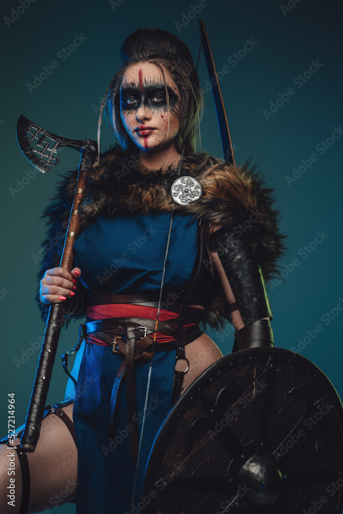 Photo of nordic huntress woman with strup back longbow holding shield and axe. Photo of nordic huntress woman with strup back longbow holding shield and axe.